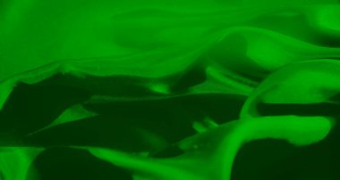 Yumuşak kıvrımlı yeşil bir kumaş, soyut ve sanatsal bir doku yaratıyor. Canlı yeşil renk ve ince gölgeleme maddenin pürüzsüz, lüks kalitesini vurgular..