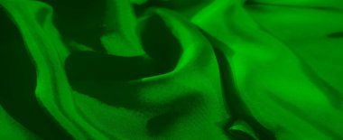 Bu yakın çekim, yeşil kumaşın zarif dokusunu ve akışını vurguluyor. Yumuşak kıvrımlar, kıvrımların ve gölgelerin soyut bir bileşimini oluşturarak dinamik ve dinamik bir sahne oluşturur..