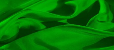 Yumuşak kıvrımlı yeşil bir kumaş, soyut ve sanatsal bir doku yaratıyor. Canlı yeşil renk ve ince gölgeleme maddenin pürüzsüz, lüks kalitesini vurgular..