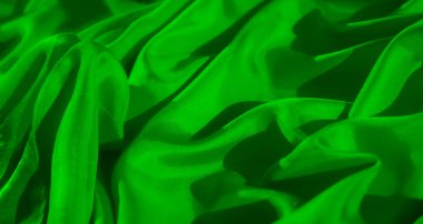 Bu görüntü kumaşın dokusunu yakına çeker, canlı yeşil maddeye derinlik katlayan nazik kıvrımlara ve gölgelere odaklanarak, hem soyut hem de ilgi çekici kılar..