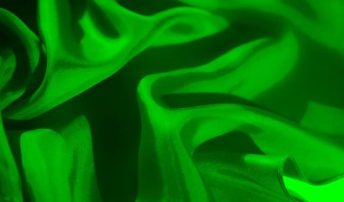 Fotoğraf, yeşil bir kumaşın dokusuna ve pürüzsüzlüğüne odaklanır. Yumuşak kıvrımlarını yakalar ve ışığın ve gölgenin gösterişli hissini vurgular..