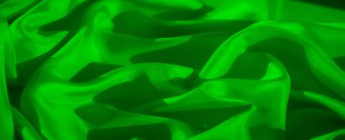 Görüntü, yüzeyindeki ışık ve gölgenin etkileşimini vurgulayan pürüzsüz yeşil bir kumaşı tasvir ediyor. Kumaşın kıvrımları lüks hissettiren zarif, akıcı bir kompozisyon yaratır.