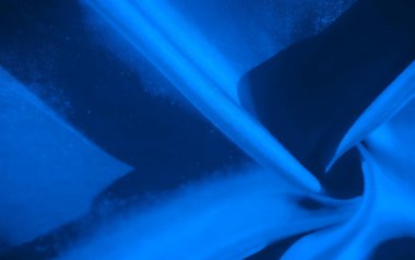 Zengin mavi renklerde akan kumaşın soyut bir tasviri. Kumaş hareket halinde görünür, hareketi yakalayan kıvrımlar ve kıvrımlar yaratır. Sofistike ve zarif bir tekstil görüntüsü.