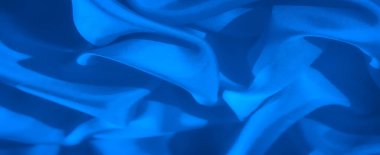 İnce kıvrımları ve dalgalı kıvrımları olan canlı mavi bir kumaş hareket ve derinlik hissi yaratıyor. Işıklandırma kumaş dokusunu geliştirir, dinamik ve soyut bir kalite ekler