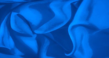 Derin kıvrımları ve yumuşak dokusu olan ipek mavisi bir kumaşın soyut görüntüsü. Işık ve gölgenin etkileşimi akışkan bir hareket yaratır, zarafet ve sükunet hissi verir..