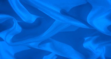 Soyut mavi kumaşın yakın plan görüntüsü yumuşak kıvrımları ve dokuları hassas dalgalarla yakalıyor. Görüntü, yumuşatıcı ve minimalist bir estetik sunarak kumaşın pürüzsüz yüzeyini vurgular..