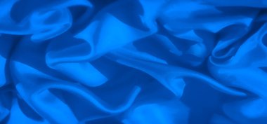 Mavi kumaşın soyut bir görüntüsü bükülmüş ve akarken, yumuşak kıvrımlar ve hafif dokular sergiliyor. Kumaşın pürüzsüz gradyanı tasarım projeleri için mükemmel ve sofistike bir atmosfer yaratıyor.