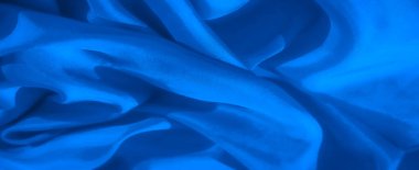 Bu soyut yakın çekim yumuşak kıvrımlarda dönen pürüzsüz mavi kumaşı yakalar, dokuya ve ışığa vurgu yapar. Gölgelerin etkileşimi minimalist tasarıma derinlik katar..