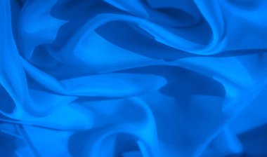 Yumuşak kıvrımlı, karmaşık dokular ve ince gölgeleme ile kaplanmış soyut bir mavi kumaş yakın plan akışkanlık ve hareket hissi yaratır..