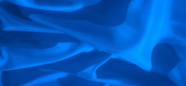 Yumuşak kıvrımlı, karmaşık dokular ve ince gölgeleme ile kaplanmış soyut bir mavi kumaş yakın plan akışkanlık ve hareket hissi yaratır..