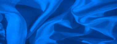Pürüzsüz dokuların ve ince kıvrımların durgun ve akıcı bir estetik oluşturduğu mavi kumaşın yakın çekimini gösteren soyut bir görüntü. Yumuşak kıvrımlar kumaşa organik ve barışçıl bir kalite veriyor..