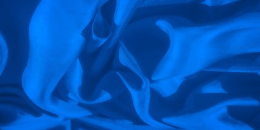 Mavi kumaşın zarif bir yakın çekimi, pürüzsüz dokusunu ve akış çizgilerini sergiliyor. Yumuşak kıvrımlar ve sakinleştirici renkler, sanatsal arkaplanlar için ideal, görsel olarak çekici soyut bir tasarım yaratır..