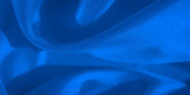 Mavi kumaşın yumuşak, akışkan bir düzeni, bu soyut yakın plan çekimde, nazik kıvrımları, pürüzsüz dokuları ve tekstil yüzeyindeki ince eğimleri vurguluyor.