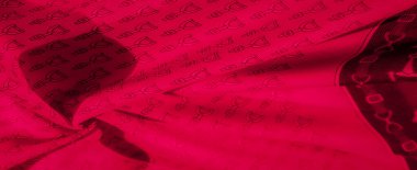 Tekrarlayan geometrik deseni olan kırmızı bir kumaşa yakın plan. Desen ve arkaplan arasındaki yüksek zıtlık kumaşların ince detaylarını vurgular ve görsel bir ilgi yaratır.