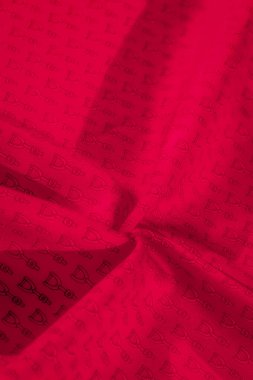 Üniformalı siyah soyut bir tasarım ile süslenmiş kırmızı kumaş, minimalist ama çarpıcı bir kontrast oluşturuyor. Kumaştaki kıvrımlar, maddenin derinliğini artıran doğal gölgeler sunuyor.