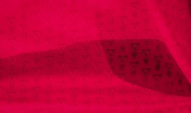 Bu görüntü, tekrarlayan siyah üzengi motifiyle süslenmiş canlı kırmızı bir kumaşı gösteriyor. Kumaşın yumuşak kıvrımları ve doğal kumaş doku ve boyut ekler.,