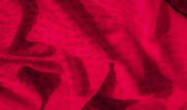 Dikensiz siyah üzengi desenli kırmızı bir kumaşa yakın plan. Kumaşın dokusu ve kıvrımları, moda ve tekstil tasarımı için mükemmel bir görsel dinamik model oluşturur..