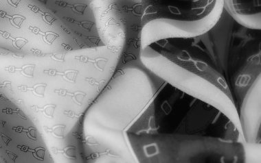 Gri tonda, üzengiye benzer şekillerin tekrarladığı bir kumaş. Kumaşın dokusu yumuşak kıvrımlar oluşturur ve tasarıma boyut ekler..