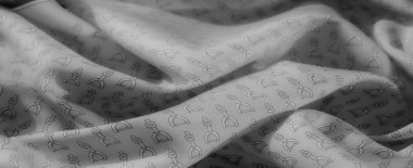 Gri tonlardaki kumaş, zarif kıvrımlarla örülmüş karmaşık üzengi desenlerine sahiptir. Monokrom palet ve pürüzsüz dokular karmaşıklığı çağrıştırıyor..