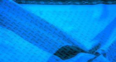 Yinelenen siyah üzengi dizaynlı canlı mavi bir tekstil. Sofistike ve soyut bir model yaratmak için yumuşakça katlanmış. Moda veya ev dekorasyonu için mükemmel..