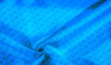 İnce siyah üzengi desenli zengin mavi bir kumaş, dokuyu ve tasarımı vurgulamak için zarif bir şekilde örtülmüş. Bu lüks tekstil, binicilikten esinlenilmiş modayı çağrıştırıyor.