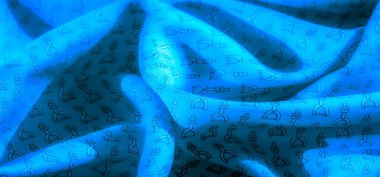 Yüzeyinde siyah üzengi deseni olan zengin mavi bir kumaş. Malzemenin yumuşak kıvrımları ışıkta ince farklılıklar yaratarak hareket ve derinlik hissi yaratıyor..