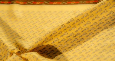 Bu resim, siyah üzengi deseniyle kaplı sarı kumaşın ince kıvrımlarını yakalar, tekstilin pürüzsüz yüzeyine derinlik ve boyut ekler ve binicilik cazibesini arttırır..