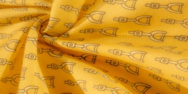 Yinelenen siyah üzengi motifiyle süslenmiş güzel bir el yapımı sarı kumaş binicilik unsurları ve modern tekstil tasarımı arasında sofistike bir denge sunuyor..