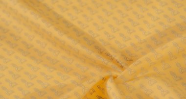 Pürüzsüz, parlak sarı bir kumaş, çarpıcı siyah üzengi desenli, binici dokunuşu ekliyor. Kumaşın ince kıvrımları boyut yaratır ve zarif tasarımı vurgular..