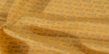 Yumuşak, sarı kumaş, karmaşık siyah üzengimsi desenlere sahip, pürüzsüz katlara karşı hassas bir tasarım sergiliyor. Kumaşın dokusu ve nazikçe örtülmesi, sofistike bir biniciden esinlenilmiş görünüm sunuyor.