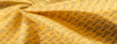 Yüzeyinde şık siyah üzengi desenli sarı kumaş. Kumaşın doğal örtüsü ve kalın üzengi motifleri, moda veya ev dekorasyonu için mükemmel, dinamik bir tekstil yaratır..