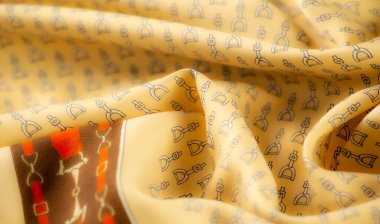 Tekrarlanan siyah üzengi desenleriyle kaplı sarı bir kumaş, şık bir binicilik estetiğini yakalıyor. Işık ve gölge oyunu tasarımın zenginliğini ve derinliğini arttırır..