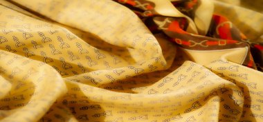 Sarı bir kumaşın yakın plan çekimi üzengiye benzer detaylı bir desen içerir. Kumaşın yumuşak kıvrımları ve karmaşık tasarımı binicilik ve tekstil için mükemmel ama zarif bir doku yaratır.