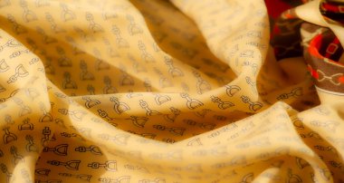 Tekrarlayan siyah üzengi desenli sarı kumaş. Kumaşın buruşuk görünümü, bu resmi moda, tekstil tasarımı veya iç dekorasyon temaları için uygun hale getirerek boyutu ekler..