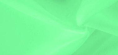 Bulanık yeşil kumaş, pürüzsüz bir akış içinde yumuşakça örtünüyor, pürüzsüz dokusu boyunca soyut bir ışık ve gölge oyunu yaratıyor. Kumaşın yumuşak hareketi bir sükunet ve zarafet hissi yaratır..