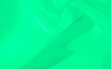 Bulanık yeşil kumaş yumuşak kıvrımlar ve hassas dalgalar oluşturuyor. Yumuşak dokusu ve ince ışık yansımaları var. Kumaşın zarif akışı, sakin ve minimalist bir güzellik hissi veriyor..