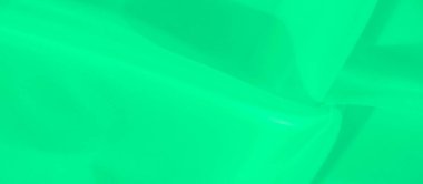 Bulanık yeşil kumaş yumuşak kıvrımlı, yumuşak kıvrımlı. Kumaşın soyut şablonu, kompozisyona sanatsal bir dokunuş ekleyerek sakin ve minimalist bir tasarım yaratıyor..