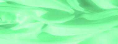 Sıvı dalgalarla kaplanmış bulanık yeşil kumaş pürüzsüz dokular ve dinamik hareketlerle büyüleyici ve soyut bir bileşim oluşturuyor. Canlı yeşil renk görüntünün enerjisini ve derinliğini arttırır..