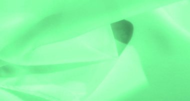 Bulanık yeşil kumaş. Sıvı kıvrımları ve kıvrımları olan çok az soyut bir bileşim. Canlı yeşil renk, pürüzsüz tekstil yüzeyine canlı bir enerji katarak derinlik ve dinamizm ekliyor..