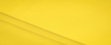 Sarı kumaşın bulanık görüntüsü yumuşak kıvrımları ve pürüzsüz bir dokusu var. Parlak sarı renk sıcaklık yayar, arka plan veya tasarım elementleri için mükemmel dinamik bir görsel yaratır..