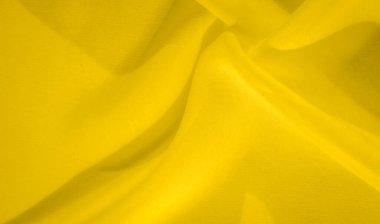 Yumuşak ve dalgalı parlak sarı kumaşın bulanık görüntüsü. Yumuşak dokusu ve canlı tonu, tekstil tasarımı veya soyut sanat görselleri için mükemmel, enerjik ama sakinleştirici bir zemin oluşturur..