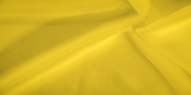 Sarı kumaşın bulanık görüntüsü yumuşak kıvrımları ve pürüzsüz bir dokusu var. Parlak sarı renk sıcaklık yayar, arka plan veya tasarım elementleri için mükemmel dinamik bir görsel yaratır..