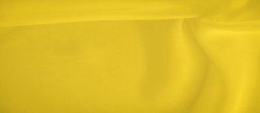 Sarı kumaşın bulanık görüntüsü yumuşak kıvrımları ve pürüzsüz bir dokusu var. Parlak sarı renk sıcaklık yayar, arka plan veya tasarım elementleri için mükemmel dinamik bir görsel yaratır..