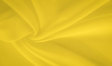 İnce kıvrımlı parlak sarı kumaşın bulanık görüntüsü, sıcak ve canlı bir estetik ile soyut bir model oluşturuyor. Yumuşak dokular ve ışık ona dinamik ve akışkan bir görünüm verir..