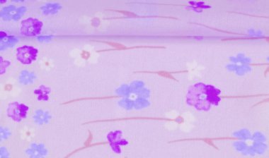 Mor arkaplana karşı mor ve mavi çiçeklerin karışımını gösteren bulanık çiçekli kumaş, baharda bahçeyi çağrıştıran ince ve havadar bir doku sunuyor..