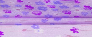 Mor arkaplana karşı mor ve mavi çiçeklerin karışımını gösteren bulanık çiçekli kumaş, baharda bahçeyi çağrıştıran ince ve havadar bir doku sunuyor..