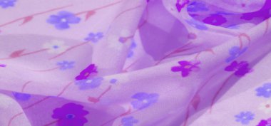 Mor kumaşın bulanık görüntüsü zarif bir çiçek deseni sergiliyor menekşe ve mavinin çeşitli tonlarında, ince pembe aksanlı. Yumuşak, akışkan dokusu zarif ve ruhani kaliteye ekleniyor..