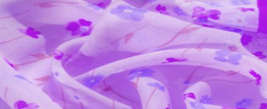 Karmaşık çiçek desenli, mor ve mavi çiçeklerin bulunduğu yumuşak lavanta kumaşın bulanık görüntüsü. Yumuşak kıvrımlar ve pürüzsüz dokular sakin ve rahatlatıcı bir atmosfer sağlar..