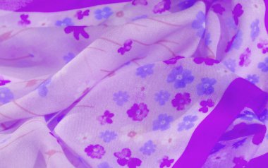 Pembe ve lavanta tonlarında çiçek desenleri içeren bulanık mor kumaş zarif bir akış yaratmak için nazikçe örtülmüş ve katlanmış yumuşaklık ve ışık hareketi için mükemmel..