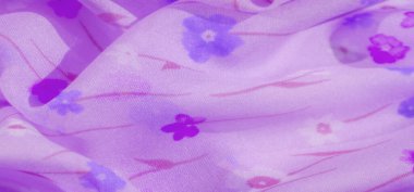 Bulanık açık mor kumaş. Mavi ve pembe renkli karışık çiçek motifleri var. Rüya gibi ve zarif bir ortam yaratan yumuşak akıcı perdeler sergiliyor..